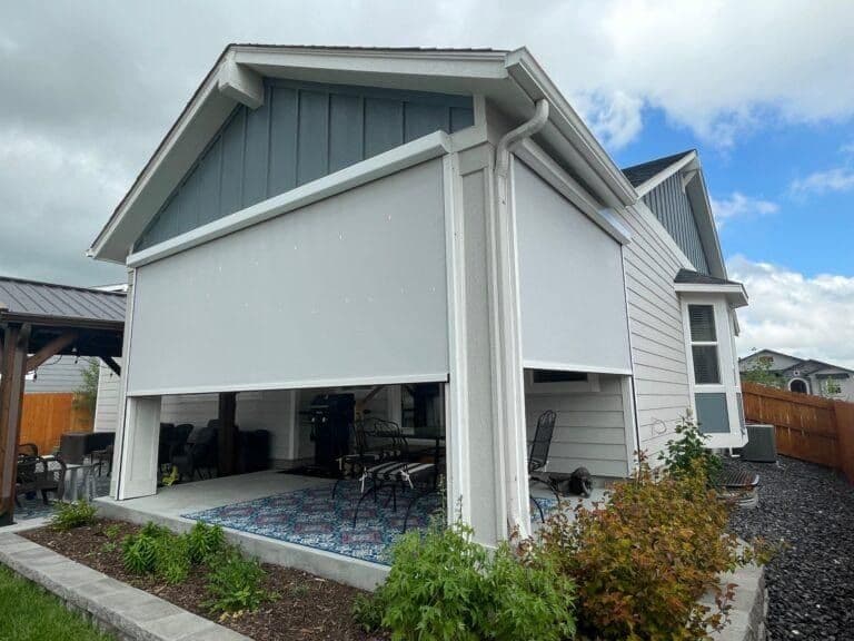 Modern residential patio with retractable shade screen, white framing, and furnished seating area beneath covered structure